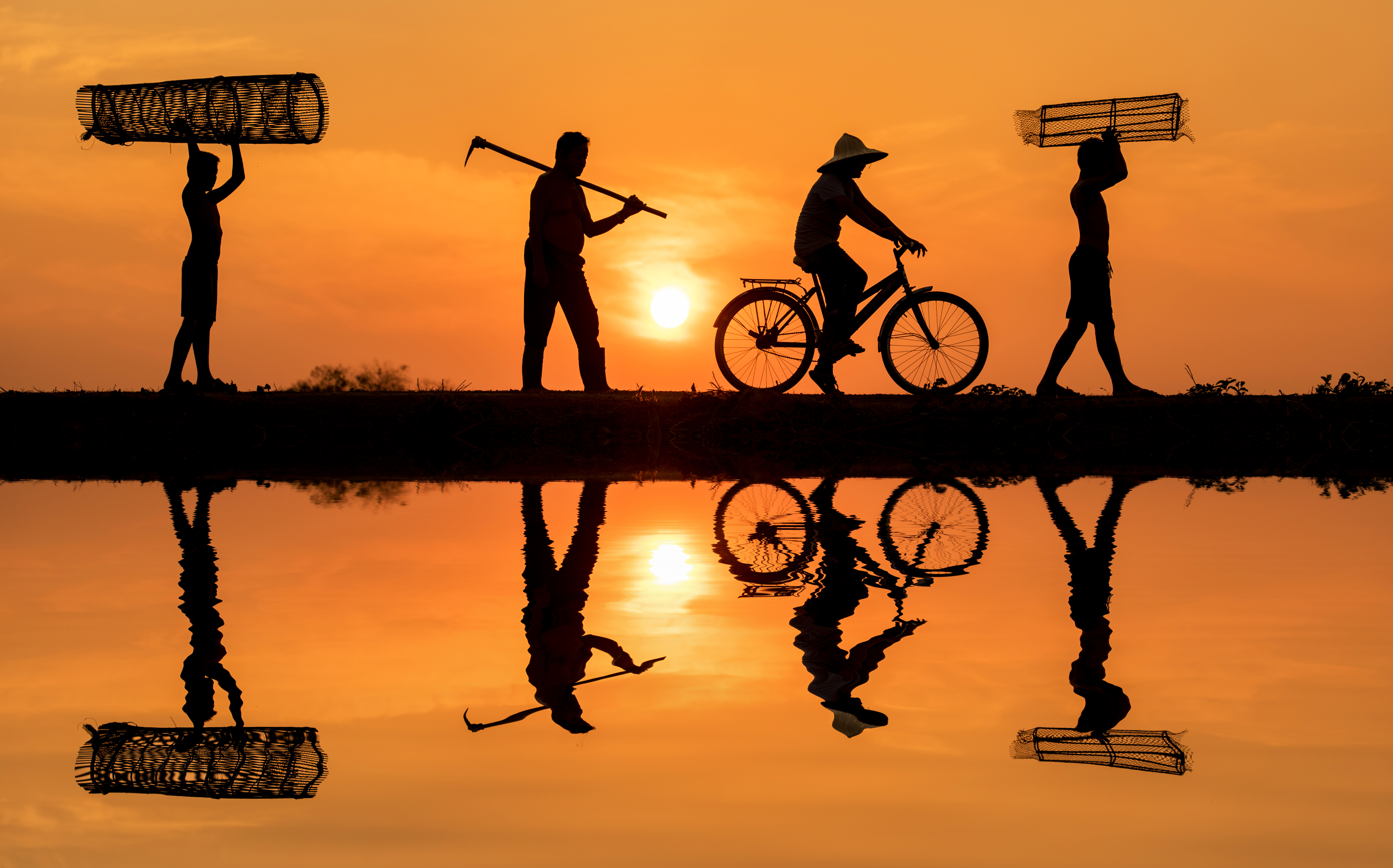 Four men on their way to work at sunrise. One is on a bicycle.